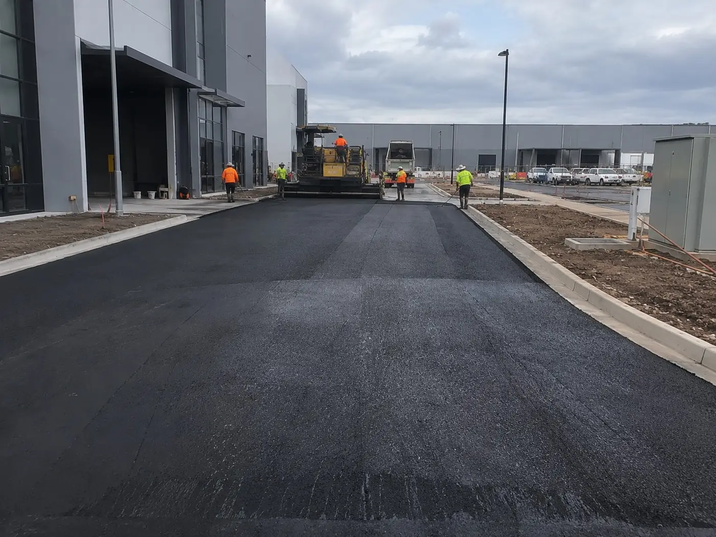 Freshly laid asphalt access road with new kerbs at an industrial estate