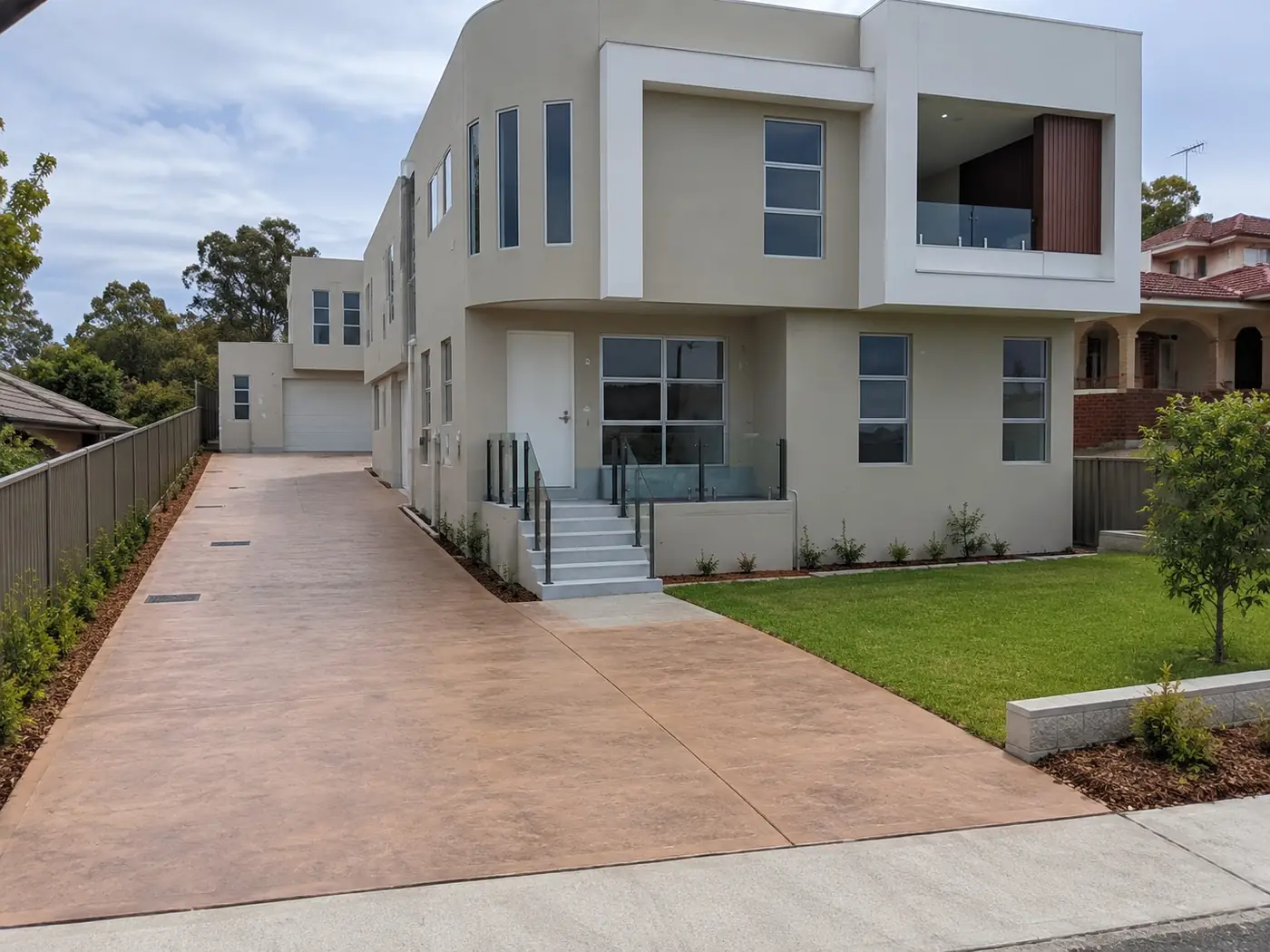 Terracotta-toned coloured concrete driveway at a new townhouse