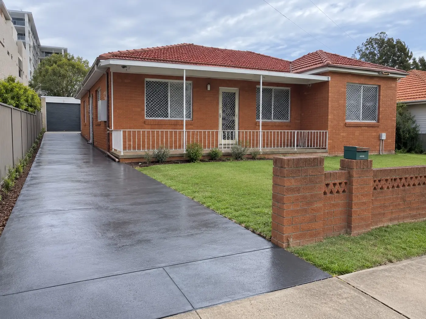 Sealed dark concrete driveway at a red-brick Wollongong home
