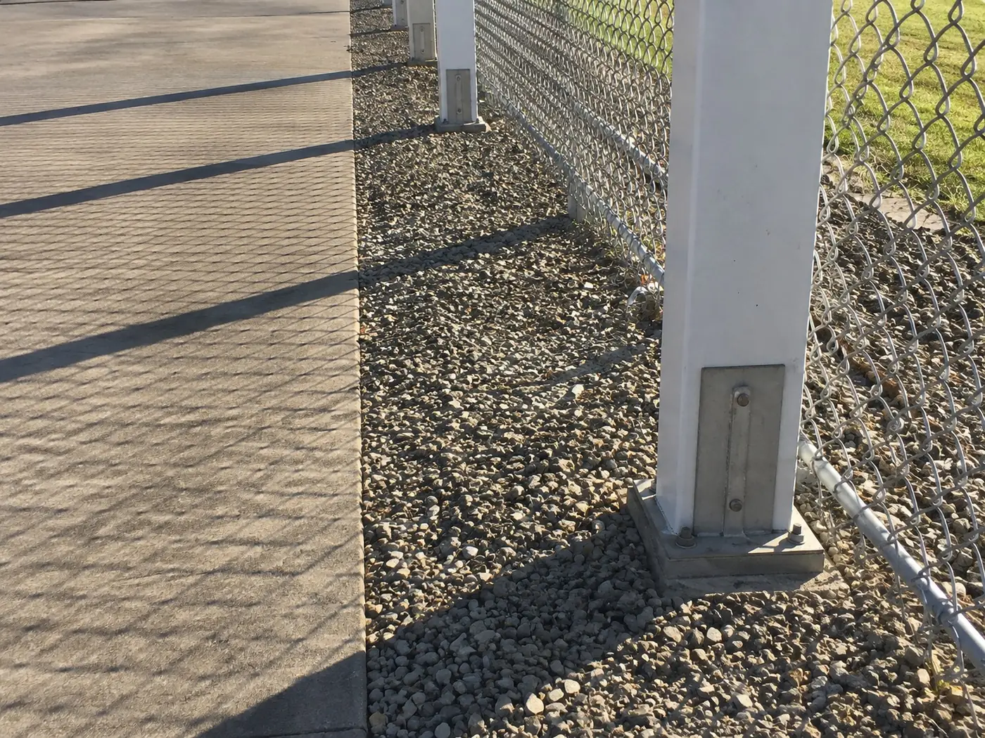 Concrete post footing set in gravel beside a coastal path