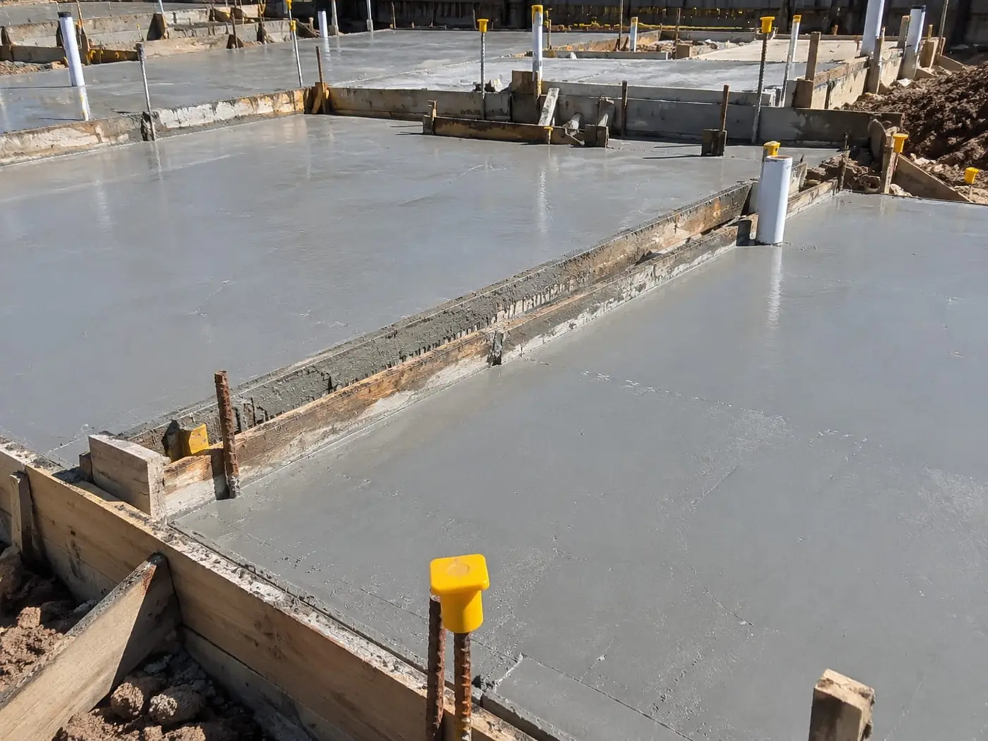 Concreter finishing a slab edge beside timber formwork in Wollongong