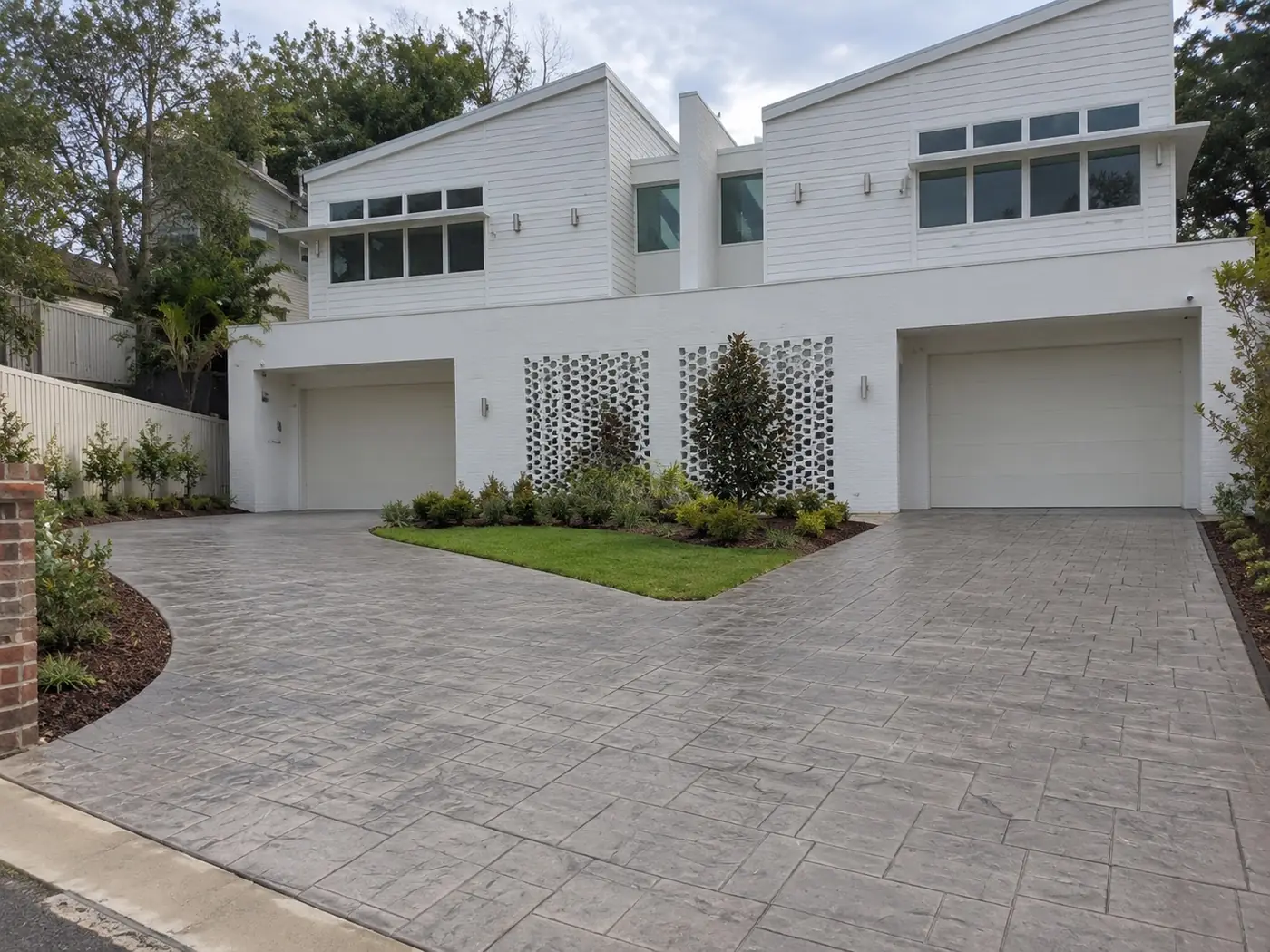 Grey stamped concrete driveway outside a double-garage duplex